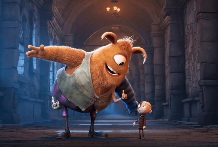 Duży, przyjazny, pomarańczowy potwór z jednym okiem i wielkimi ramionami uśmiecha się i gestykuluje, rozmawiając z małym chłopcem w pasiastej koszuli wewnątrz wielkiego kamiennego korytarza ze świecącymi światłami.