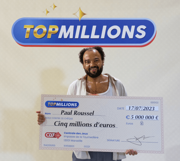 Uśmiechnięty mężczyzna trzyma duży czek na pięć milionów euro, datowany na 17.07.2023 r., z loterii TOPMILLIONS. Czek jest wystawiony na Paula Roussela. Nad nim widnieje logo TOPMILLIONS.