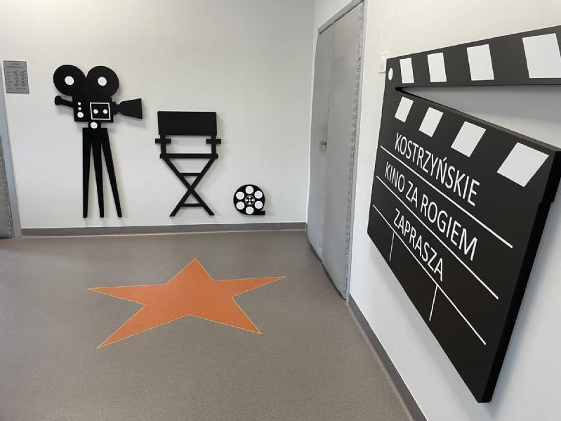 Korytarz ozdobiony filmową grafiką ścienną, w tym kamerą filmową, krzesłem reżysera, rolką filmu i dużym klapsem z polskim tekstem. Na podłodze znajduje się pomarańczowa gwiazda, przywodząca na myśl wygląd Hollywoodzkiej Alei Gwiazd.