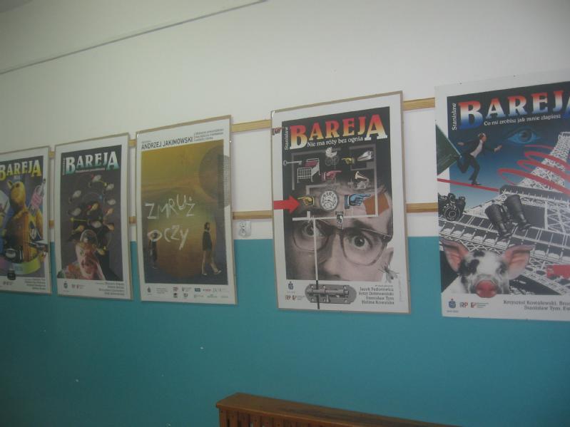 Pięć kolorowych plakatów filmowych, głównie z napisem BAREJA, jest wyświetlanych w rzędzie na niebiesko-białej ścianie. Plakaty przedstawiają różne projekty graficzne i obrazy związane z filmem.