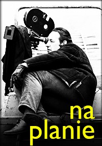 Osoba siedzi obok dużego zabytkowego aparatu filmowego, patrząc przez wizjer. Obraz jest czarno-biały, z polskimi słowami na planie w pogrubionym żółtym tekście w prawym dolnym rogu.