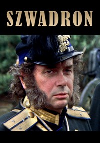 Mężczyzna w mundurze wojskowym ze złotymi detalami i dużymi bokobrodami patrzy poważnie w kamerę. Nosi ciemny kapelusz ze złotym emblematem. Nad jego głową widnieje pogrubione słowo SZWADRON.