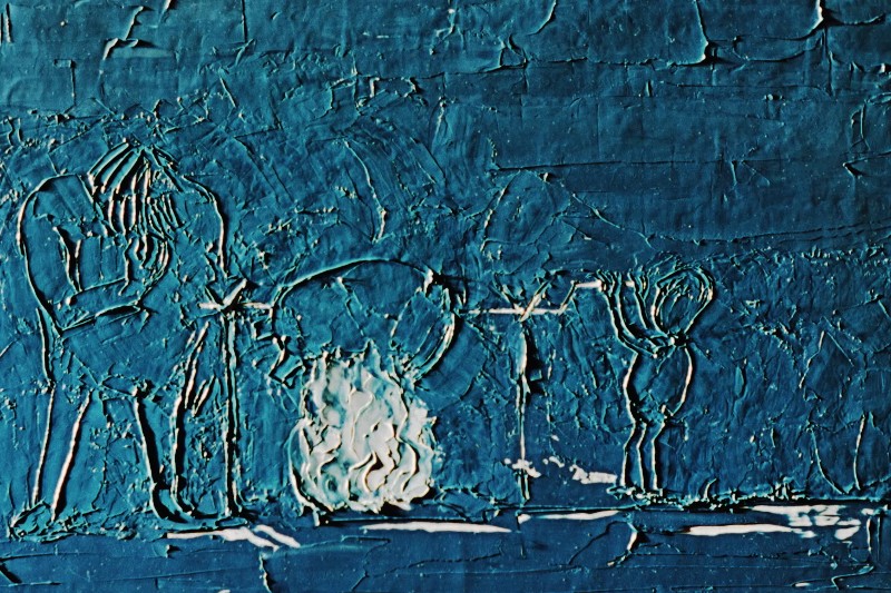 Teksturowany niebieski obraz przedstawiający dwie abstrakcyjne postacie ludzkie stojące przy ognisku; jedna postać wydaje się większa i pochylona, podczas gdy druga jest mniejsza z uniesionymi ramionami. Scena wydaje się prymitywna lub starożytna.
