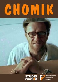 Mężczyzna w okularach i z brodą, ubrany w białą koszulę, przyciska dłoń do szklanej powierzchni. Na górze widnieje napis CHOMIK dużymi pomarańczowymi literami, a na dole loga studia i stowarzyszenia filmowego.