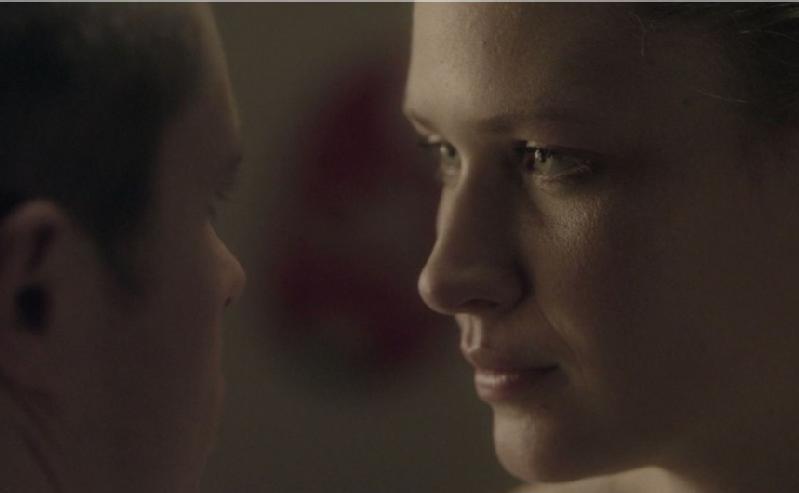 Zbliżenie na dwie osoby stojące naprzeciwko siebie w intymnej relacji. Delikatne oświetlenie podkreśla zamyślony wyraz twarzy kobiety, gdy patrzy w oczy drugiej osobie.