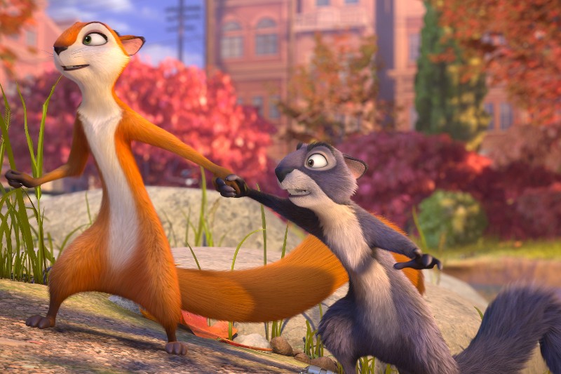 Dwa animowane zwierzęta, wiewiórka pomarańczowo-biała i wiewiórka szaro-biała, trzymają się za ręce, stojąc na zewnątrz w kolorowym, jesiennym parku z czerwonymi drzewami i budynkami w tle.