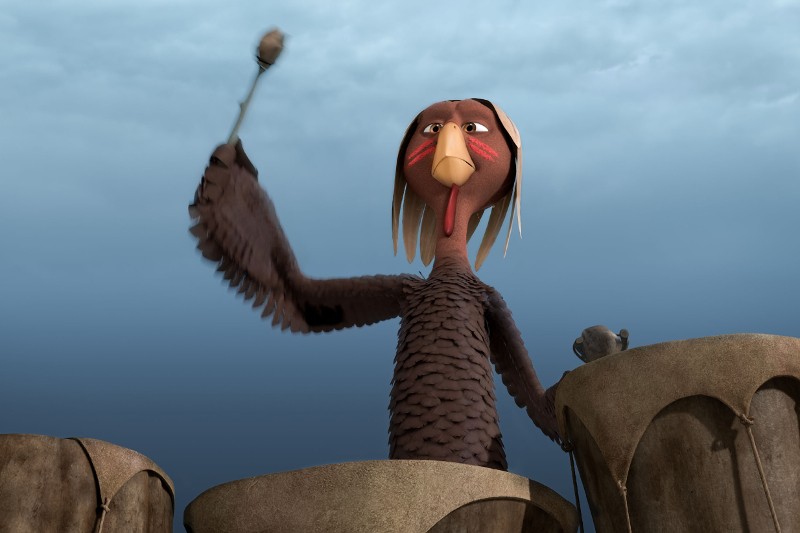 Animowana postać ptaka o ludzkich rysach, czerwonych znaczeniach na policzkach i upierzonym ciele gra na dużych bębnach na zewnątrz, pod zachmurzonym niebem.
