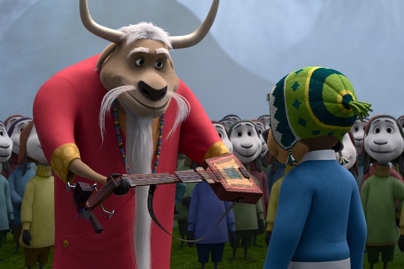 Animowany jak ubrany w czerwoną szatę i z długą, białą brodą podaje domowej roboty gitarę dziecku w niebieskiej kurtce i zielonej zimowej czapce, w tle widać gromadę owiec.