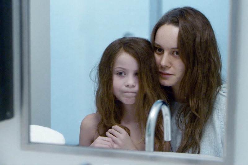 Młoda kobieta i mała dziewczynka z długimi brązowymi włosami stoją blisko siebie, patrząc na swoje odbicie w lustrze w łazience. Obie mają poważne miny. Na pierwszym planie widoczny jest srebrny kran.