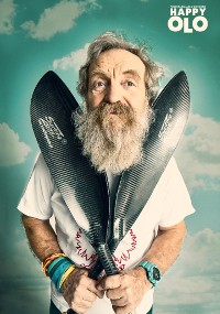 Starszy mężczyzna z długą, siwą brodą trzyma dwa czarne wiosła skrzyżowane przed klatką piersiową. Ma na sobie biały t-shirt, kolorowe opaski na nadgarstki, zegarek i stoi na tle nieba z napisem HAPPY OLO w prawym górnym rogu.