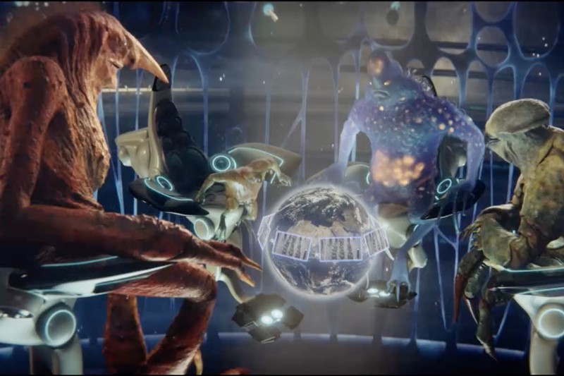 Cztery pozaziemskie istoty o niepowtarzalnym wyglądzie siedzą na futurystycznych krzesłach, zgromadzone wokół holograficznej Ziemi otoczonej pasmami DNA, wewnątrz nowoczesnego pomieszczenia ze świecącymi na niebiesko elementami.