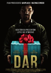 Mężczyzna stoi w ciemności, trzymając niebieskie pudełko z czerwoną kokardą. Polski tekst pojawia się nad pudełkiem i na nim. Tytuł DAR jest dużymi żółtymi literami na dole. Ogólny ton jest pełen napięcia i tajemniczości.