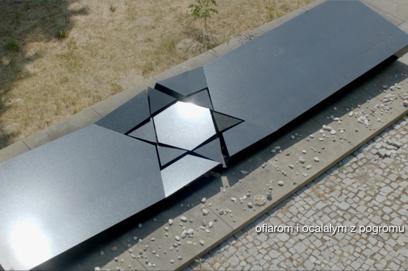 Pomnik z czarnego kamienia z wyciętą Gwiazdą Dawida, otoczony małymi kamieniami, stoi obok brukowanej ścieżki. Tekst po polsku brzmi: ofiarom i ocalałym z pogromu.