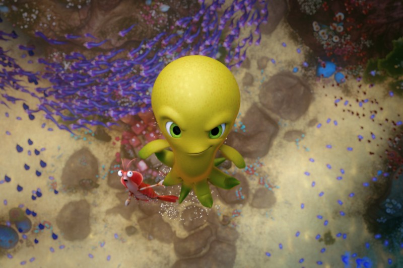 Żółta animowana ośmiornica o figlarnym wyrazie twarzy unosi się pod wodą obok małej, czerwono-białej ryby w paski. Kolorowe korale i skały są widoczne na dnie oceanu pod nimi.