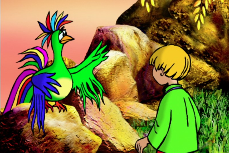 Kolorowy rysunkowy ptak o tęczowych piórach rozmawia z blondwłosym chłopcem w zielonej koszuli, siedzącym na zewnątrz wśród skał i trawy na tle zachodzącego słońca.