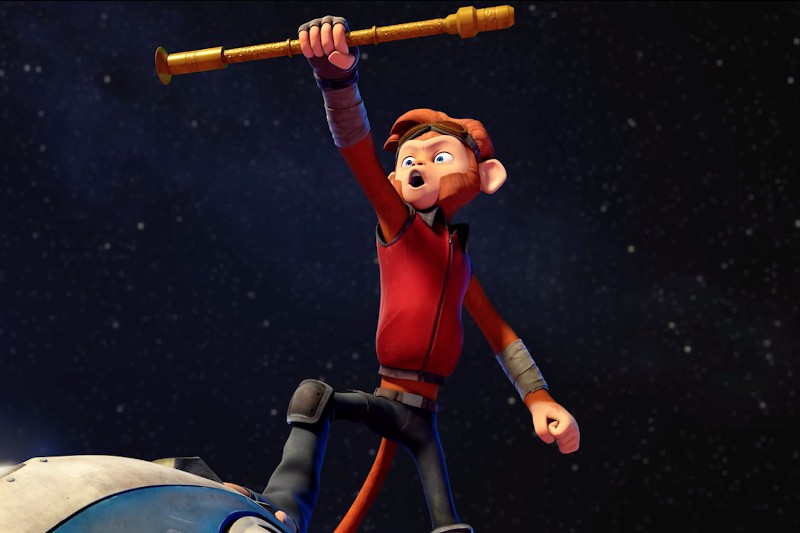 Animowana postać małpy w czerwonej kurtce bohatersko stoi, opierając jedną nogę na niebieskim przedmiocie, unosząc złotą laskę na tle rozgwieżdżonego nieba.