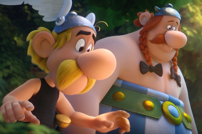 Dwie animowane postacie z dużymi nosami, jedna szczupła z żółtymi wąsami i skrzydlatym hełmem, druga większa z czerwonymi warkoczami i ubraniem w niebieskie paski, stoją blisko siebie na świeżym powietrzu, w zielonym otoczeniu.