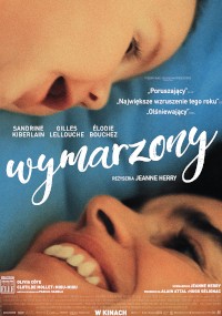 Zbliżenie twarzyczki dziecka patrzącego na uśmiechniętą kobietę, na plakacie biały napis oznaczający tytuł filmu „Wymarzony” oraz nazwiska obsady i ekipy filmowej.