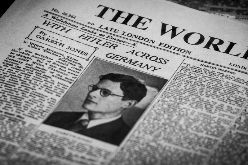 Czarno-biała gazeta z nagłówkiem „Z Hitlerem przez Niemcy” i portretem mężczyzny w okularach. Artykuł jest autorstwa Garetha Jonesa i ukazał się w Late London Edition of The World.