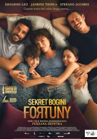 Cztery osoby, dwie osoby dorosłe i dwoje dzieci, leżą blisko siebie na łóżku, uśmiechając się do kamery. Obraz jest plakatem filmowym do Sekret Bogini Fortuny z napisami i tekstem w języku polskim.