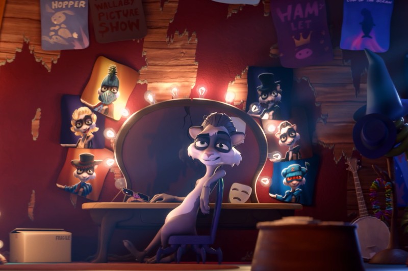 Szop siedzi przy toaletce otoczonej świecącymi żarówkami i kolorowymi plakatami przedstawiającymi różne postacie zwierząt w kostiumach. W pokoju jest łuszcząca się tapeta i panuje teatralna, kapryśna atmosfera.