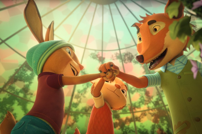 Trzy antropomorficzne zwierzęta — królik, lis i młodsze zwierzę — stoją razem w szklanej kopule, uśmiechając się radośnie i podnosząc ręce w geście celebracji. Światło słoneczne sączy się przez liściasty sufit nad nimi.