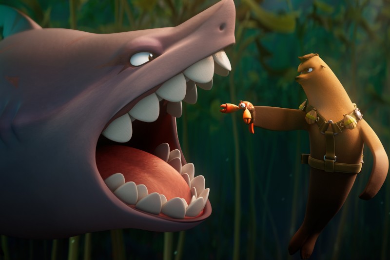 Ożywiony rekin z szeroko otwartą paszczą staje twarzą w twarz z wydrą w uprzęży, która trzyma na rękach małego kraba, dumnie kryjącego się pod wodą wśród zielonych roślin.
