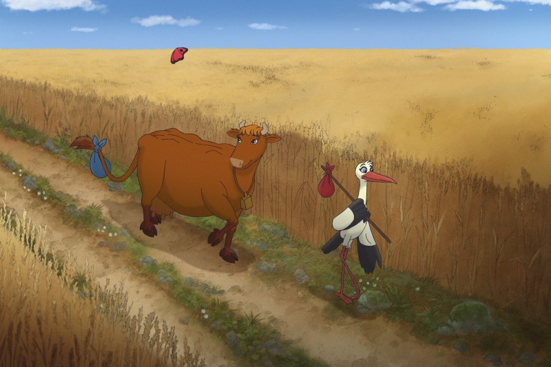 Kreskówkowa krowa i bocian idą ścieżką przez złote pole pszenicy, każdy niosący mały czerwony pakunek na patyku. Ptak przelatuje nad nimi na niebieskim niebie z rozproszonymi chmurami.