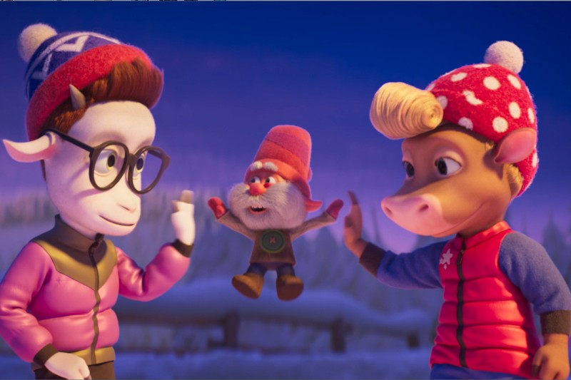 Dwie animowane postacie reniferów w zimowych ubraniach przybijają sobie piątki, podczas gdy mały krasnal w czerwonej czapce wiwatuje między nimi na tle zaśnieżonego terenu.