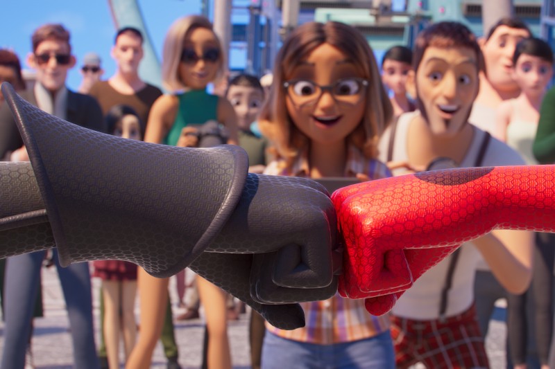 Dwóch superbohaterów, jeden w czarnym, a drugi w czerwonym garniturze, przybijają sobie piątkę na pierwszym planie, podczas gdy w tle widać tłum podekscytowanych, uśmiechniętych ludzi, którzy przyglądają się i wiwatują.