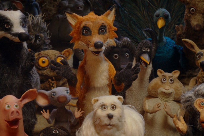 Grupa animowanych kukiełek przedstawiających zwierzęta, w tym lisa, borsuka, sowy, świnię, pawia, mysz i inne, pozuje razem i patrzy w stronę kamery z wyrazem zaskoczenia lub zaciekawienia.