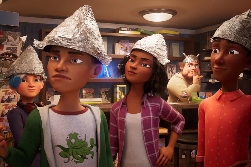 Pięć animowanych postaci w czapeczkach z folii aluminiowej stoi razem w pokoju wypełnionym książkami i plakatami. Wyglądają poważnie i ciekawie, a jedna osoba z tyłu w zamyśleniu dotyka jej brody.