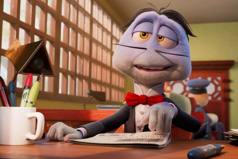 Kreskówkowy królik w garniturze i czerwonej muszce siedzi przy biurku, trzyma gazetę i wygląda na zrelaksowanego. Na biurku są długopisy, kubek i lampa. Inna postać jest rozmazana w tle.