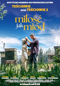 Mężczyzna pomaga kobiecie założyć strój pszczelarza na polu z ulami. Niebo jest niebieskie z chmurami. Tytuł polskiego filmu Miłość jak miód i nazwiska obsady pojawiają się powyżej i poniżej sceny.