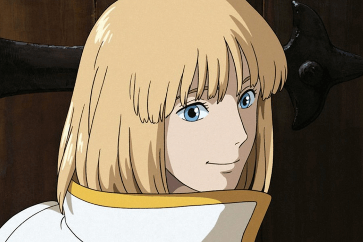 Animowana postać z prostymi, sięgającymi do brody blond włosami, niebieskimi oczami i białym płaszczem z wysokim kołnierzem uśmiecha się delikatnie. Za nimi widać ciemne, rozmyte tło z częścią dużego, czarnego obiektu.