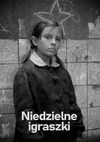 Młoda dziewczyna z warkoczykami i poważnym wyrazem twarzy stoi przy kafelkowej ścianie z rysunkami kredą. Na dole widnieje polski tekst Niedzielne igraszki. Obraz jest czarno-biały.