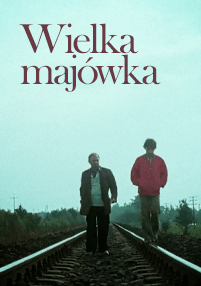 Dwie osoby idą po torach kolejowych pod zachmurzonym niebem. Tekst Wielka majówka pojawia się na górze obrazu dużymi, czerwonymi literami. W tle widać drzewa i linie energetyczne.