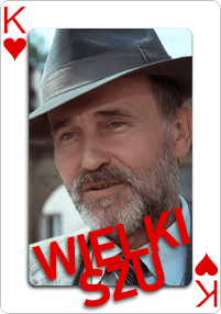 Karta do gry przedstawiająca Króla Kier z mężczyzną w garniturze i kapeluszu. Na karcie dużymi czerwonymi literami napisano słowa WIELKI SZU.