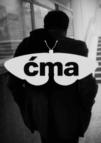 Osoba w ciemnym płaszczu idzie korytarzem, widziana od tyłu. Nałożony jest obraz ćmy ze słowem ćma (po polsku ćma) napisanym na jej skrzydłach.