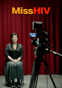 Kobieta w ciemnej sukience siedzi przed czerwoną zasłoną, zwrócona twarzą do kamery wideo na statywie. Na górze obrazu widnieje tekst Miss HIV w pogrubionych żółtych i czerwonych literach.