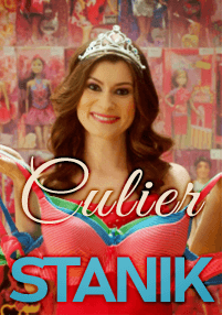 Uśmiechnięta kobieta z długimi brązowymi włosami, ubrana w tiarę i jasną sukienkę, trzyma przed sobą kolorowe biustonosze. W tle widać lalki w pudełkach, a na obrazie widnieje napis Culier STANIK.