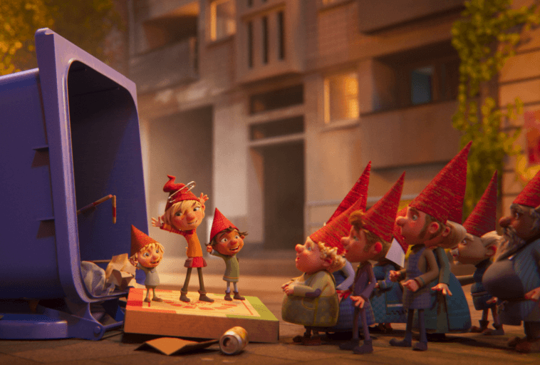 Grupa animowanych gnomów w czerwonych czapkach gromadzi się wokół otwartego niebieskiego kosza na śmieci i pudełka po pizzy na ulicy miasta, wyglądając na podekscytowanych, gdy jeden z gnomów stoi z podniesionymi rękami.