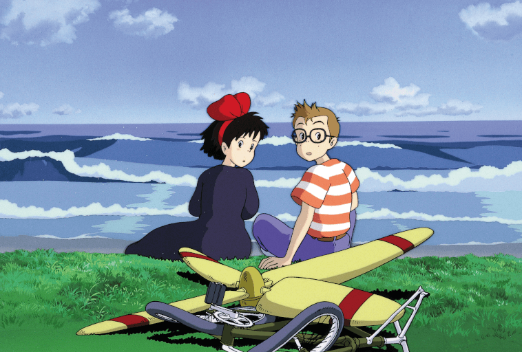 Dwie animowane postacie siedzą na trawie nad oceanem, patrząc w stronę widza. Jedna z nich nosi czerwoną kokardę i ciemną sukienkę, a druga okulary i koszulę w paski. Na pierwszym planie leży żółty zepsuty rower. W tle widoczne są fale.