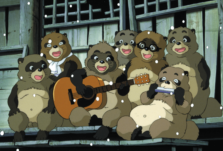 Grupa animowanych tanuki, z których niektóre grają na instrumentach takich jak gitara i harmonijka ustna, siedzi razem na drewnianej werandzie, a wokół nich pada śnieg. Wyglądają na wesołych i zrelaksowanych.